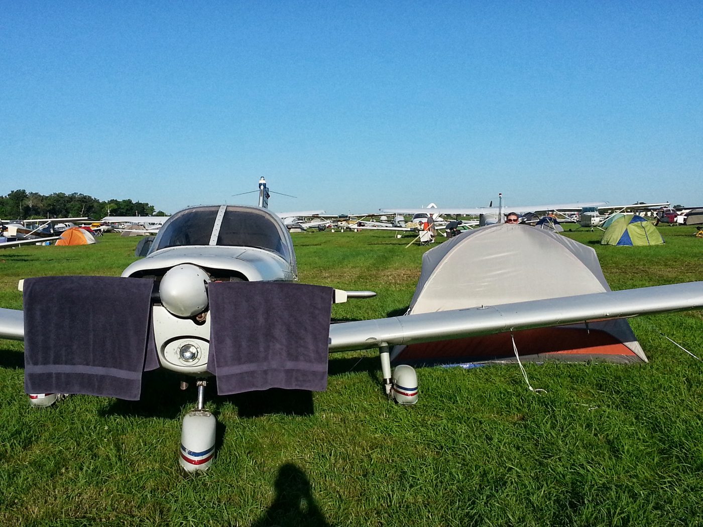 Low-wing airplane with towels drying on the wings, tent behind